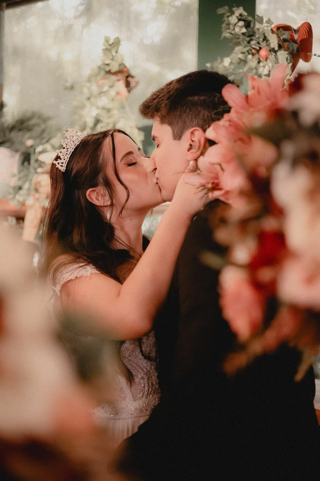 Um beijo dos noivos entre as flores da cerimônia