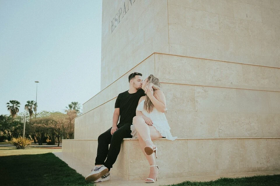 Um encontro do casal, com luz natural e arquitetura ao fundo, no pré-wedding